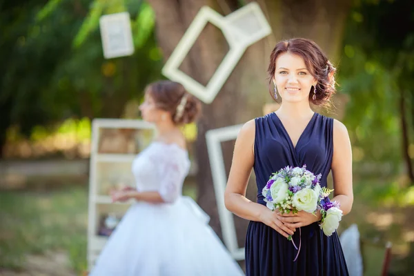 Bela noiva com dama de honra no jardim — Fotografia de Stock