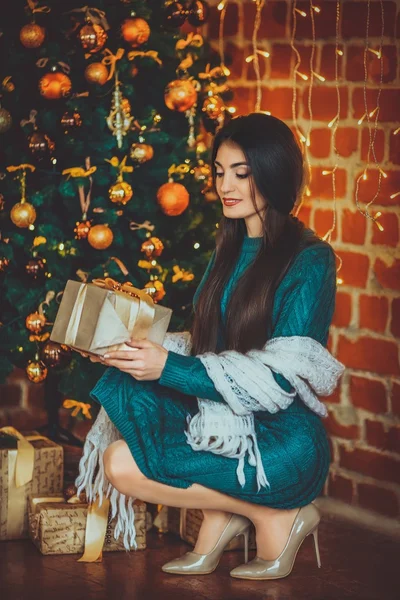 Žena s dárkem u vánočního stromu — Stock fotografie