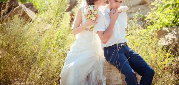 Noiva e noivo sentados na pedra — Fotografia de Stock