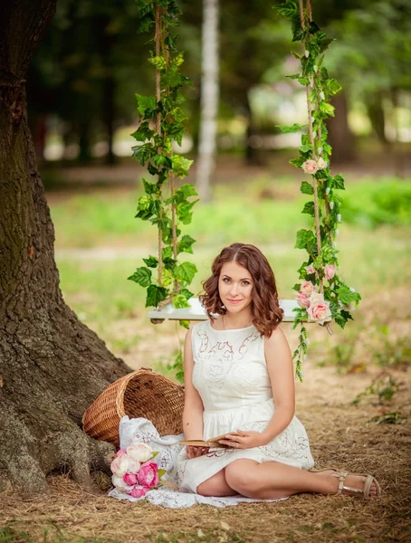 Vrouw met boek van bloemen in de tuin — Stockfoto