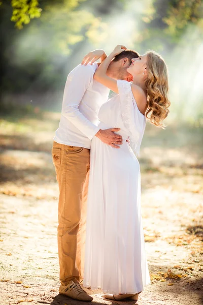 Pregnant woman with her husband in garden — Stock Photo, Image