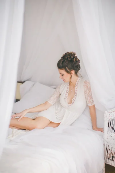 Mooie brunette meisje in wit slaapkamer — Stockfoto