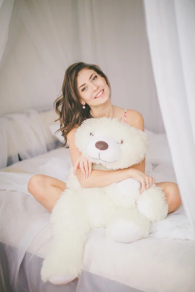 Брюнетка с игрушечным медведем в спальне — стоковое фото