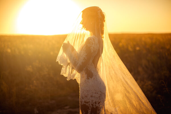 Beautiful bride in white dress at sunset