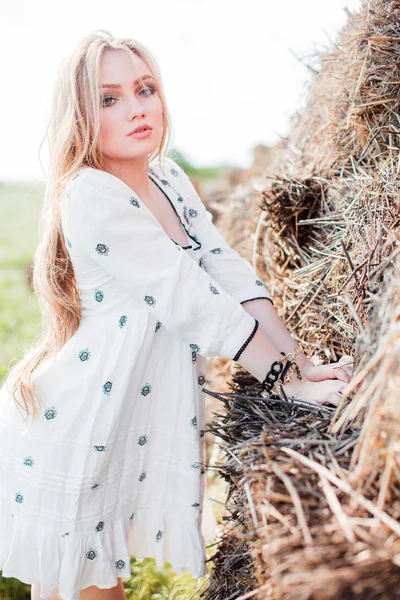 Девушка позирует возле сена в поле — стоковое фото