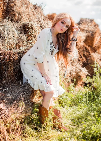Flicka som poserar nära hö i fältet — Stockfoto