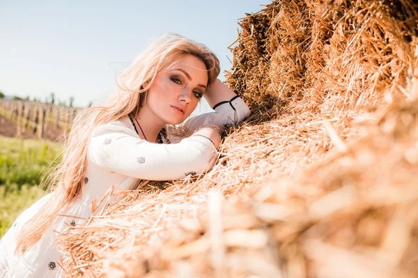 Meisje poseren in de buurt van hay in het veld — Stockfoto