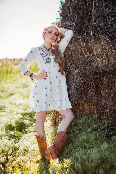 Flicka som poserar nära hö i fältet — Stockfoto
