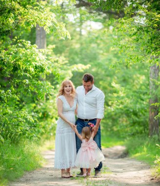 Hamile kadınla kocası ve kızı bahçede