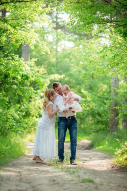 Hamile kadınla kocası ve kızı bahçede