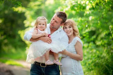 Hamile kadınla kocası ve kızı bahçede