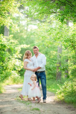 Hamile kadınla kocası ve kızı bahçede