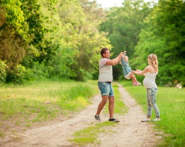 Hamile kadınla kocası ve kızı bahçede