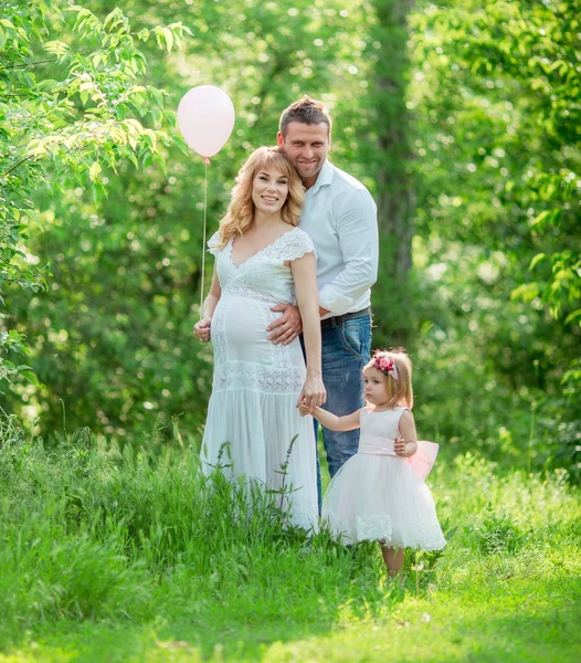 Donna incinta con il marito e la figlia in giardino — Foto Stock