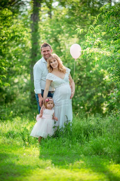 Pregnant woman with her husband and daughter in garden — Stock Photo, Image