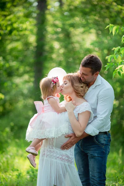 Těhotná žena se svým manželem a dcerou v zahradě — Stock fotografie