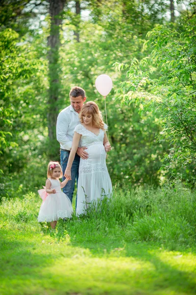 Donna incinta con il marito e la figlia in giardino — Foto Stock