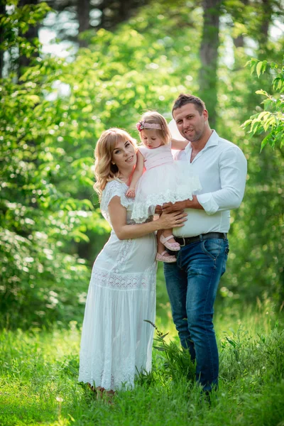 Těhotná žena se svým manželem a dcerou v zahradě — Stock fotografie