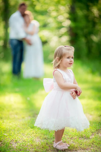 Kleines Mädchen mit Eltern im grünen Garten — Stockfoto
