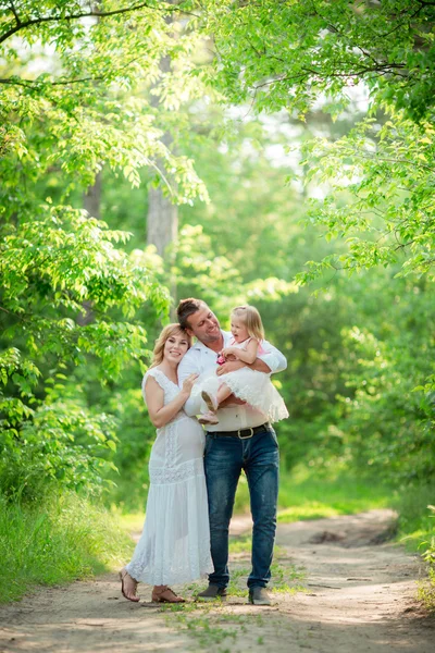 Mujer embarazada con su marido y su hija en el jardín —  Fotos de Stock
