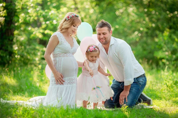 Pregnant woman with her husband and daughter in garden — Stock Photo, Image