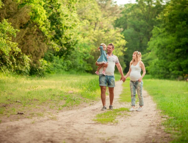 Donna incinta con il marito e la figlia in giardino — Foto Stock