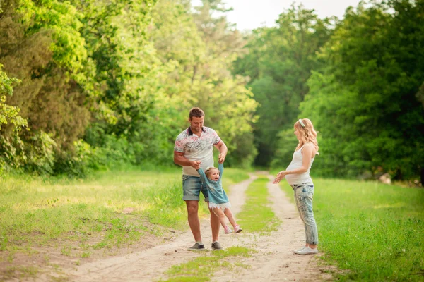 Gravid kvinne med mann og datter i hagen – stockfoto