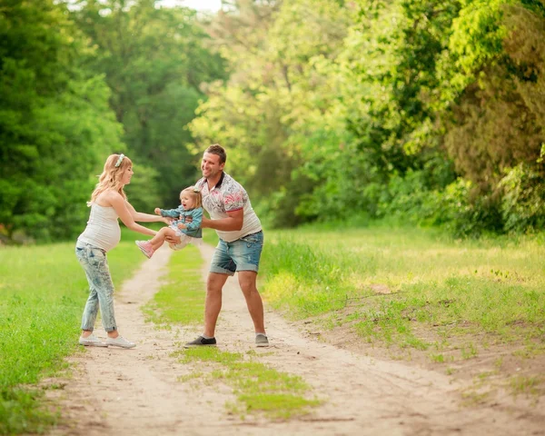 Gravid kvinne med mann og datter i hagen – stockfoto