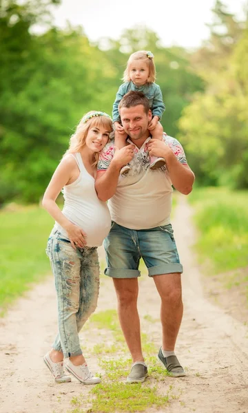 Donna incinta con il marito e la figlia in giardino — Foto Stock