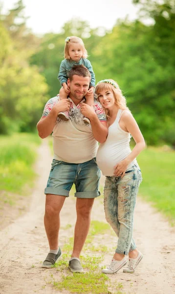 Donna incinta con il marito e la figlia in giardino — Foto Stock