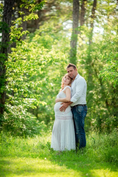 Беременная женщина с мужем в саду — стоковое фото