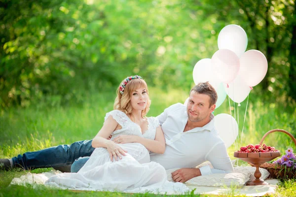 Pregnant woman with her husband in garden — Stock Photo, Image