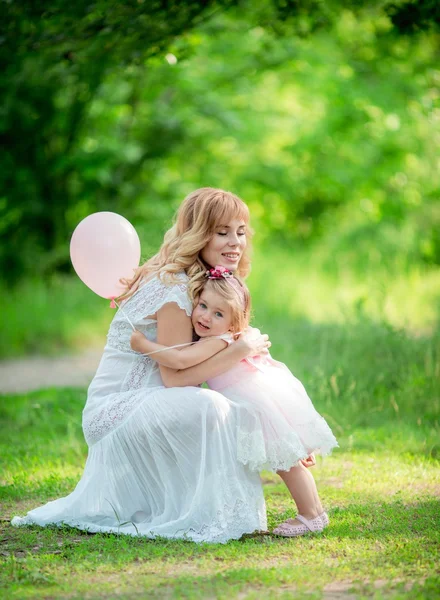 Gravid kvinna med unga dotter i trädgården — Stockfoto