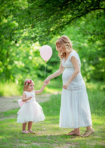Pregnant woman with young daughter in garden — Stock Photo, Image