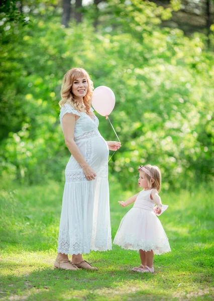 Pregnant woman with young daughter in garden — Stock Photo, Image