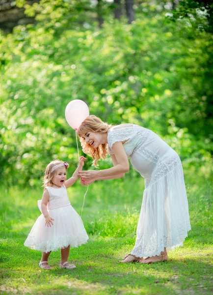 孕妇与年幼的女儿在花园里 — 图库照片