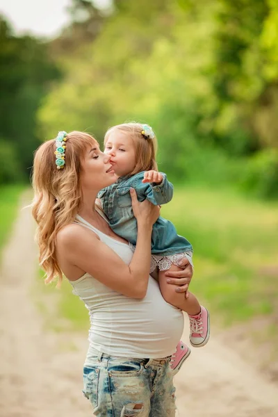 Gravid kvinne med ung datter i hagen – stockfoto