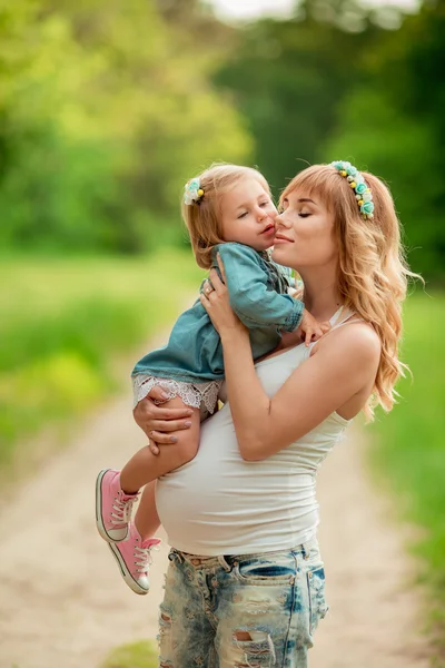 Zwangere vrouw met jonge dochter in tuin — Stockfoto