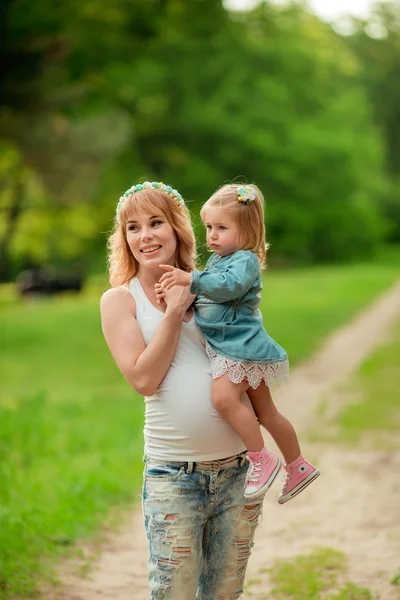 Gravid kvinna med unga dotter i trädgården — Stockfoto