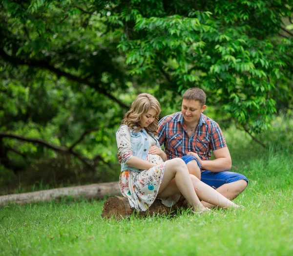 Pregnant woman with her husband in garden — Stock Photo, Image