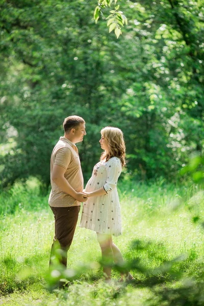 Mujer embarazada con su marido en el jardín — Foto de Stock