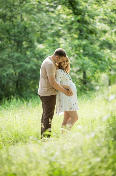 Zwangere vrouw met haar echtgenoot in de tuin — Stockfoto