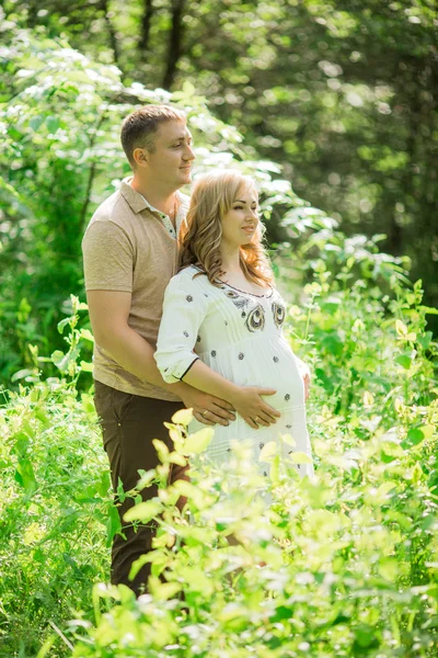 Беременная женщина с мужем в саду — стоковое фото