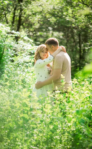 Pregnant woman with her husband in garden — Stock Photo, Image