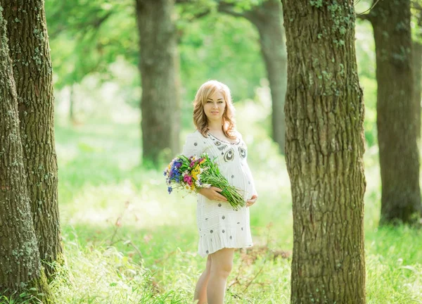 Femme enceinte avec un bouquet dans la nature — Photo