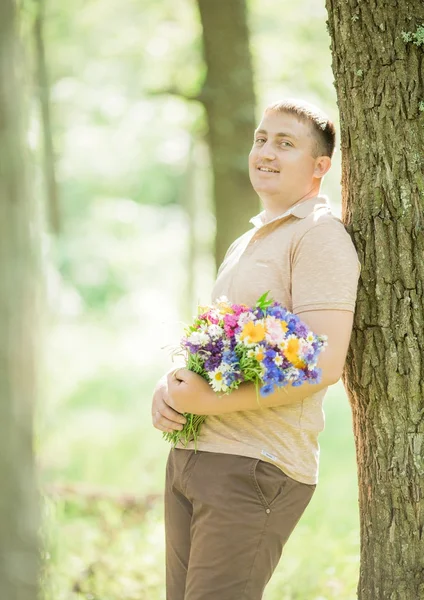 Jonge man met een bouquet van veldbloemen — Stockfoto