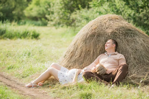 Donna incinta con il marito che riposa vicino al fieno — Foto Stock