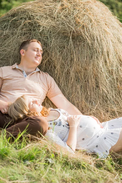 Schwangere mit ihrem Mann, der in der Nähe von Heuhahn ruht — Stockfoto