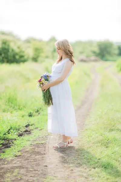 Femme enceinte avec un bouquet dans la nature — Photo