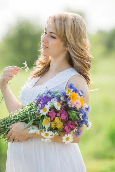 Zwangere vrouw met een boeket in de natuur — Stockfoto